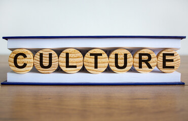 Concept word 'culture' on wooden circles between pages of a book on a beautiful wooden table. White...