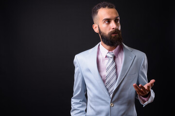 Young handsome Persian businessman with dreadlocks against black background