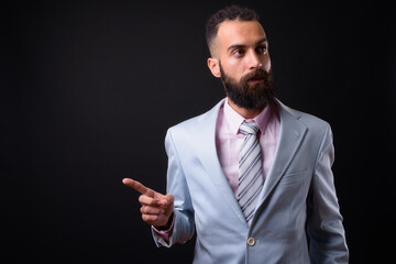 Young handsome Persian businessman with dreadlocks against black background