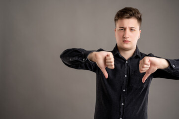 Portrait of serious stylish attractive man dressed in casual black shirt showing double dislike gesture