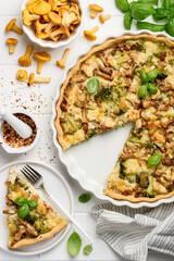 Homemade lorraine quiche or pie with chicken, broccoli and chanterelles on a white background. Tart with meat and mushrooms. Top view