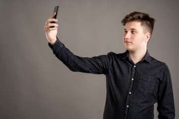 Portrait of serious stylish attractive man dressed with a casual black shirt taking selfie photo