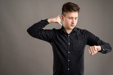 Portrait of serious stylish attractive man dressed with a casual black shirt showing calling or contact gesture