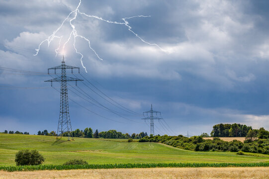 On the sultry, hot summer day, looming storm clouds appear in the sky on the upper Au area near the small town of Trossingen and lightning strikes the high-voltage pylon.