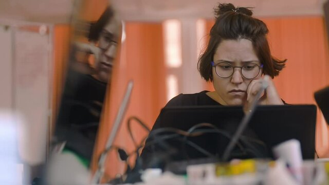stressed woman at laptop in messy workplace. irrl worried displeased female look at laptop screen reading bad unpleasant email. sad student or office worker. concept small business news