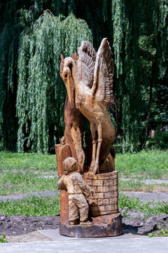 Ukraine, Khmelnytsky. July 2020. Wooden sculpture of a crane and a boy in a city park