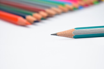 Obraz premium Close up picture of a blue pencil front of a line of different color wood pencils