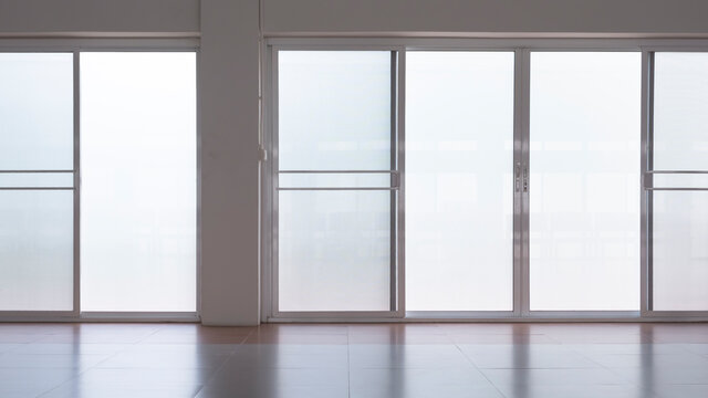 Front view of frosted glass sliding doors with screen doors and light reflection on tile floor surface in empty room 