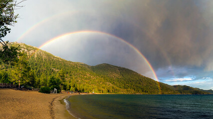 Colorful double rainbow over waves on Sand Harbor beach at Lake Tahoe Nevada