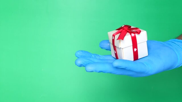 male hand in a blue medical glove gives a gift.