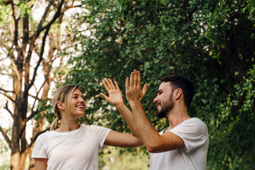 Healthy fit and sportive couple hi five and smile face in nature at summer day. Athletic couple...