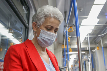 Fototapeta na wymiar elegant elderly woman in a medical mask rides the subway