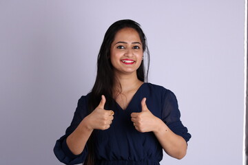 Closeup portrait of young pretty woman with two thumbs up sign gesture pointing at you, isolated on...