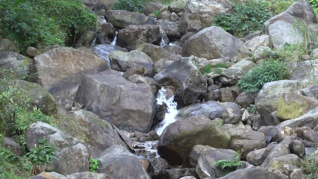Waterfall passing through rocks and green vegetation. Footage shot at Jhalong, Dooars, West Bengal - India.