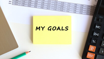 The inscription on the yellow sticky notes near to the laptop and calculator on the white office desk. Business concept.