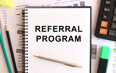 Notepad with text REFERRAL PROGRAM on a white background, near calculator and office supplies. Business concept.