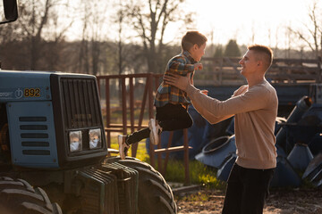 father with his little son having a good time on the farm near the tractors on sunny autumn day....