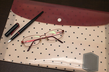 Glasses, fountain pen and document file on table