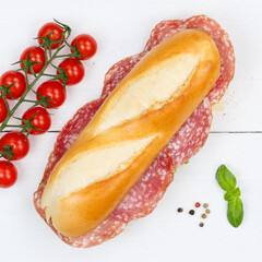 Sub sandwich baguette with salami square from above on wooden board