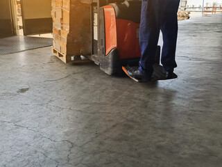 Worker driving forklift loading and unloading shipment carton boxes and goods on wooden pallet from container truck to warehouse cargo storage in logistics and transportation industrial 