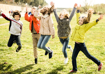 children jump up on lawn in park