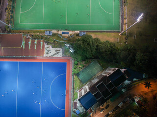 Aerial bird’s eye view of the outdoor hockey field at night. The image contains soft-focus,...