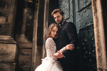 Wedding couple hugs near the vintage green door. Stone walls in ancient town background. bride with...