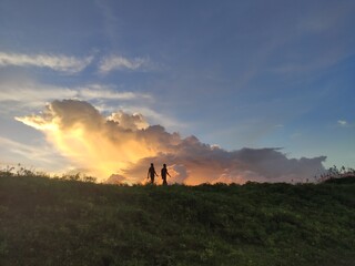 silhouette of a woman and men in the sunset