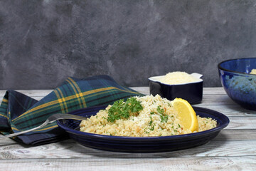 Cauliflower rice with parmesan and a parsley garnish and lemon wedge with copy space.