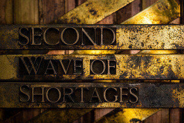 Second Wave of Shortages text formed with real authentic typeset letters on vintage textured silver grunge copper and gold background