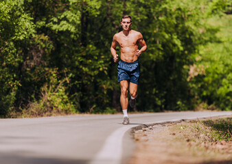 Young strong male fitness model during run outdoors in beautiful landscape