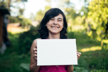 Teen girl holding clean white sheet paper (banner for your message)