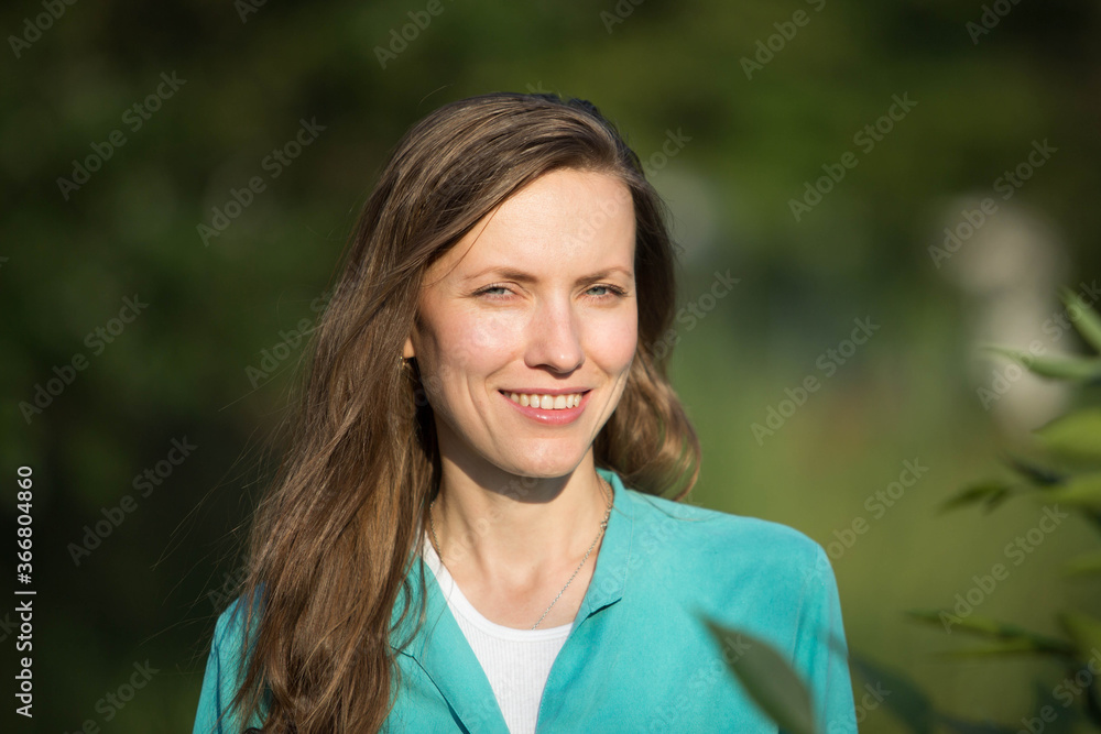 Wall mural portrait of a young woman with long hair, natural woman outdoor portrait over green grass park backg