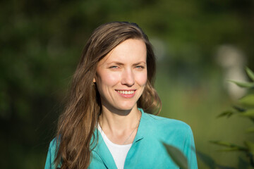 portrait of a young woman with long hair, natural woman outdoor portrait over green grass park background