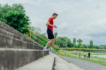 Fit male athlete performing stairs workout, running up climbing stairs performing outdoor track cardio..
