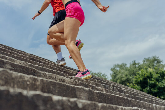 Close up and low below angle view photo of athletes legs running up concrete stairs