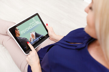 A young woman sits and calls an online psychologist during home quarantine. Video call to the doctor on a digital tablet.