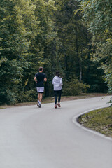 Athletic couple running on a street next to each other. Nature,fit and healthy concept.