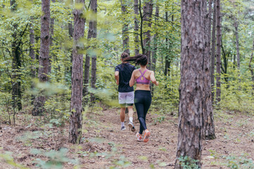 Naklejka na ściany i meble Fit male and female athletes running in nature. Nature and sports concept.