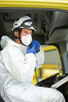 Side view serious firefighter wearing respirator and helmet sitting in fire car