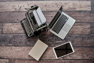From above of retro typewriter placed on table with agenda and modern netbook and tablet
