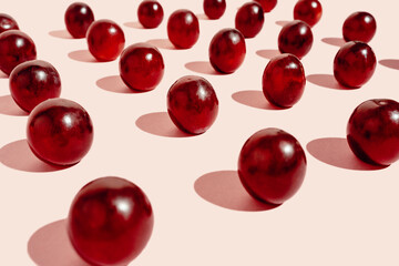 From above pattern of fresh red grapes arranged in lines on pink surface in studio