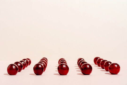 Pattern of fresh red grapes arranged in lines on pink surface in studio