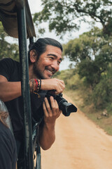 Happy traveling male with professional photo camera taking photos of wildlife during safari