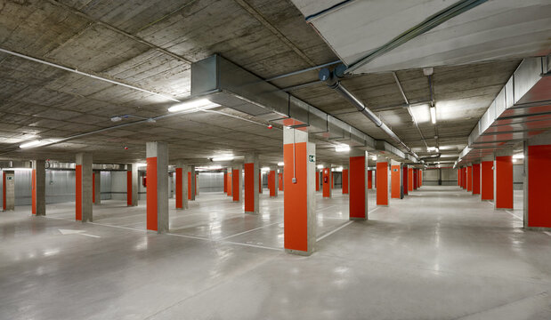 Modern parking lot with yellow stone columns and concrete floor located underground