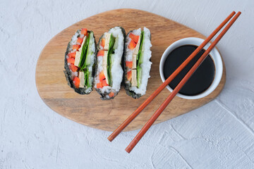 Onigirazu, vegan sushi sandwich with vegetables (cucumber, pepper, spinach) and tofu, served with soy sauce. Trend Japanese food.