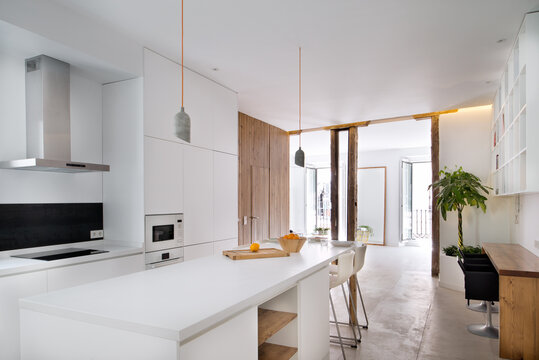 Interior of contemporary kitchen in Scandinavian style with dining table and bar stools
