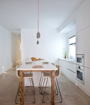 Interior of contemporary kitchen in Scandinavian style with dining table and bar stools