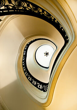 From below white elegant spiral stairway with black ornamental banister located inside classic building