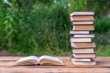 Stack of books on wooden table over nature background, outdoors